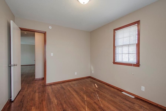 unfurnished room featuring wood finished floors, visible vents, and baseboards