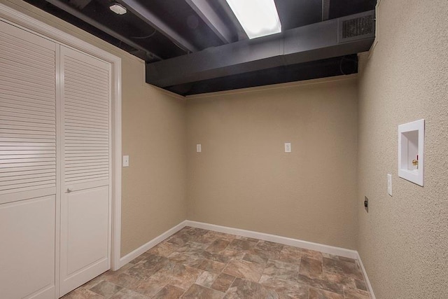 finished basement featuring baseboards, visible vents, and stone finish flooring