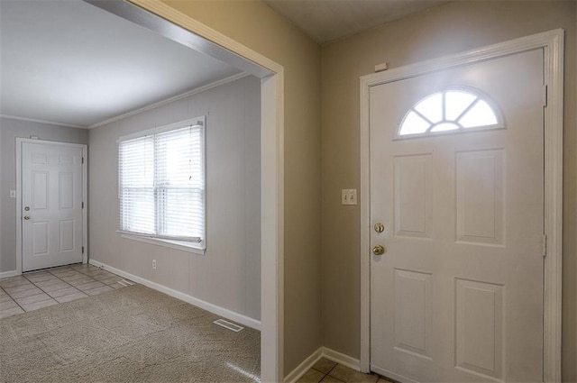 foyer entrance with visible vents, baseboards, ornamental molding, light carpet, and light tile patterned floors