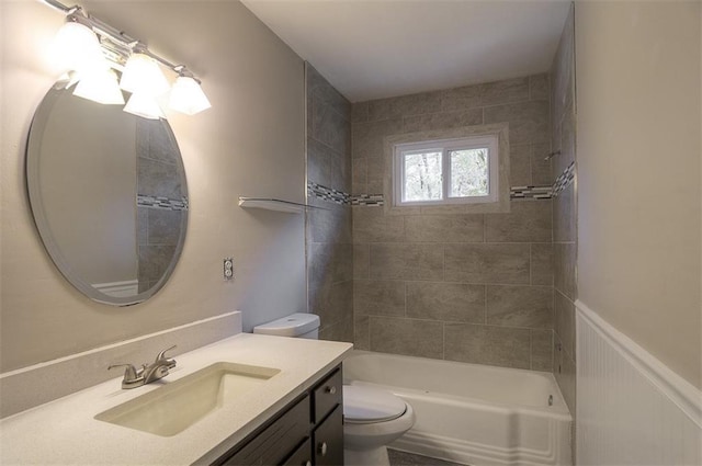 bathroom with shower / bath combination, toilet, a wainscoted wall, and vanity