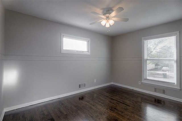 spare room with ceiling fan, dark wood-style floors, visible vents, and baseboards