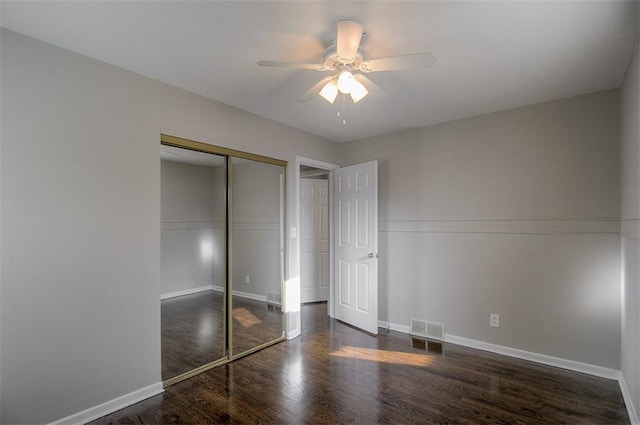 unfurnished bedroom featuring visible vents, baseboards, a closet, and wood finished floors