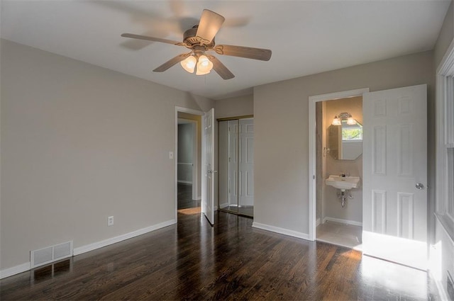 unfurnished bedroom with visible vents, ensuite bath, wood finished floors, a closet, and baseboards