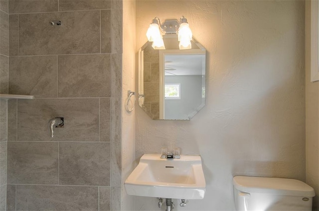 bathroom with toilet, a textured wall, and a sink