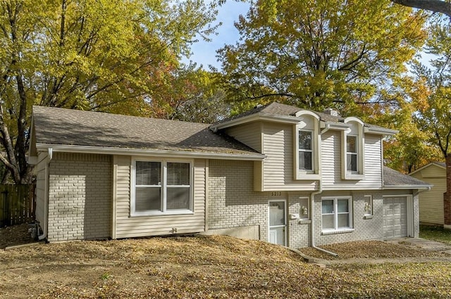 tri-level home featuring a garage, brick siding, and a shingled roof