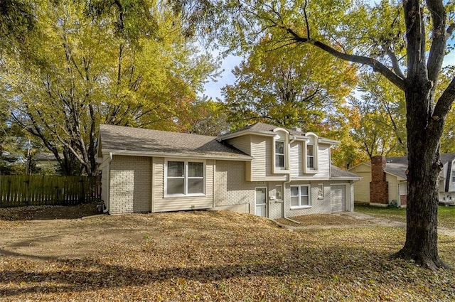 split level home with a garage, fence, and brick siding