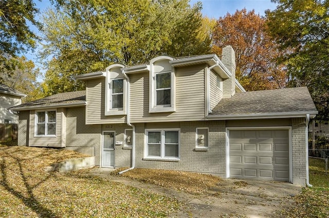 split level home with concrete driveway, brick siding, a garage, and a chimney