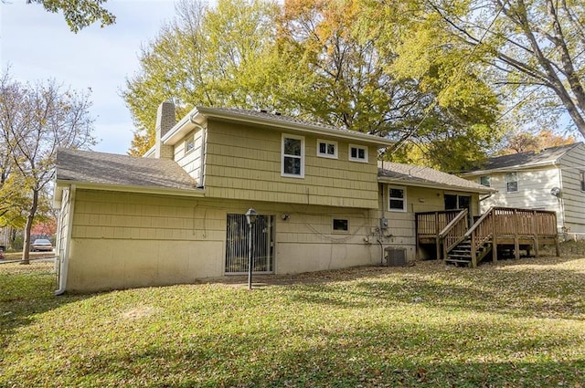 rear view of house featuring cooling unit, a wooden deck, a yard, a shingled roof, and a chimney