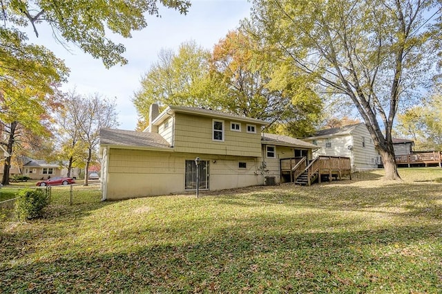 back of property with a chimney, a lawn, fence, and a wooden deck