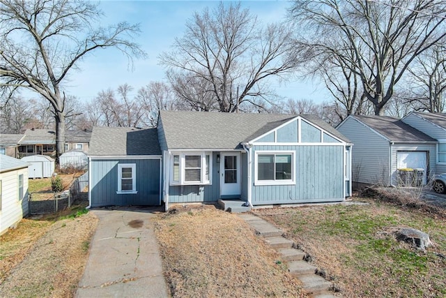 view of front facade featuring fence, board and batten siding, driveway, and a shingled roof