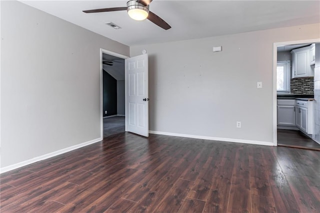 spare room with visible vents, baseboards, dark wood finished floors, and a ceiling fan