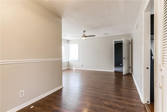 unfurnished room featuring dark wood finished floors, visible vents, a ceiling fan, and baseboards