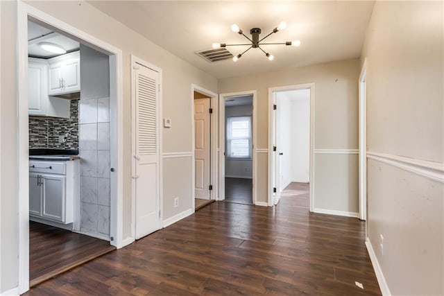 interior space featuring dark wood-type flooring, baseboards, and a chandelier