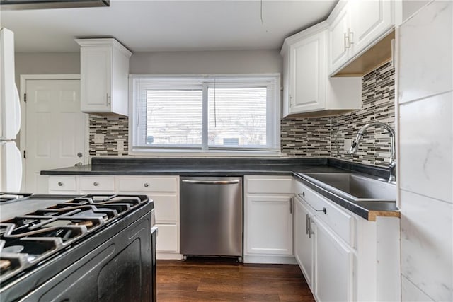 kitchen featuring dark countertops, dark wood finished floors, dishwasher, white cabinetry, and a sink