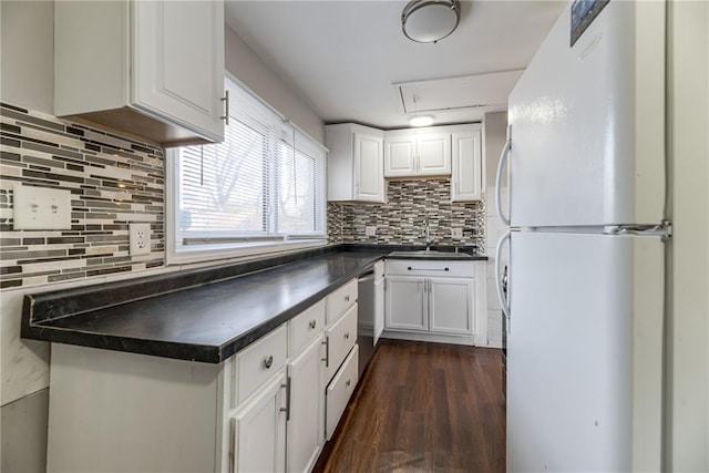 kitchen with a sink, dark countertops, white cabinetry, freestanding refrigerator, and dishwasher