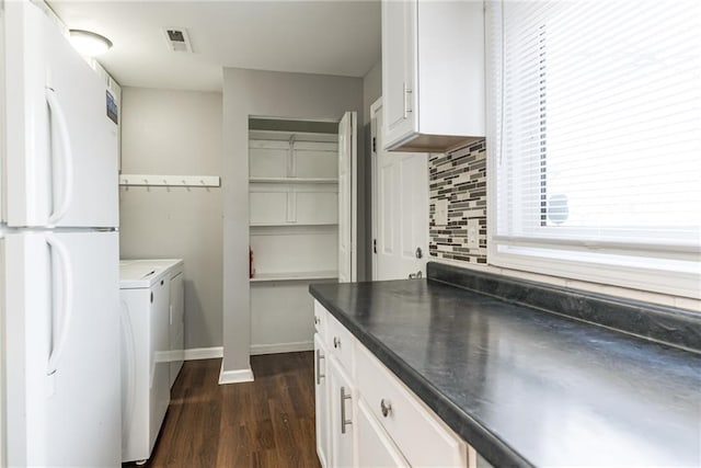 washroom featuring visible vents, washing machine and dryer, laundry area, baseboards, and dark wood-style flooring