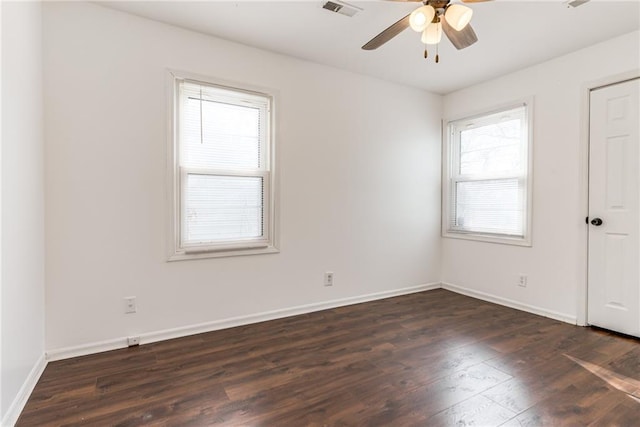 spare room featuring visible vents, plenty of natural light, baseboards, and dark wood-style floors