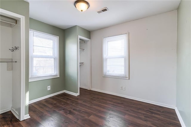 unfurnished bedroom with visible vents, baseboards, and dark wood-type flooring