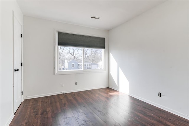 empty room featuring hardwood / wood-style floors, baseboards, and visible vents