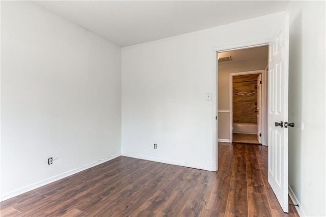 spare room featuring visible vents, baseboards, and dark wood-style flooring