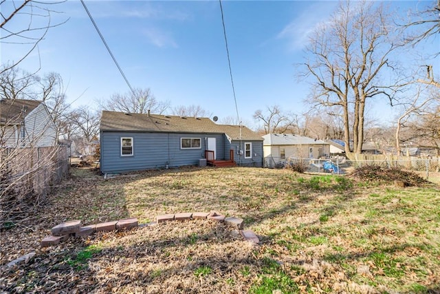 rear view of house featuring a lawn and a fenced backyard