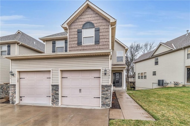 traditional home with central AC unit, a front lawn, concrete driveway, a garage, and stone siding