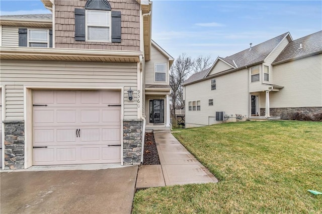 view of front facade with a front yard, an attached garage, stone siding, and central AC