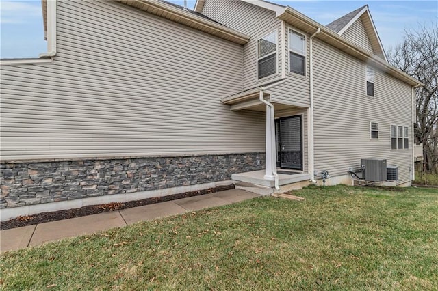 view of side of home with central AC unit and a lawn