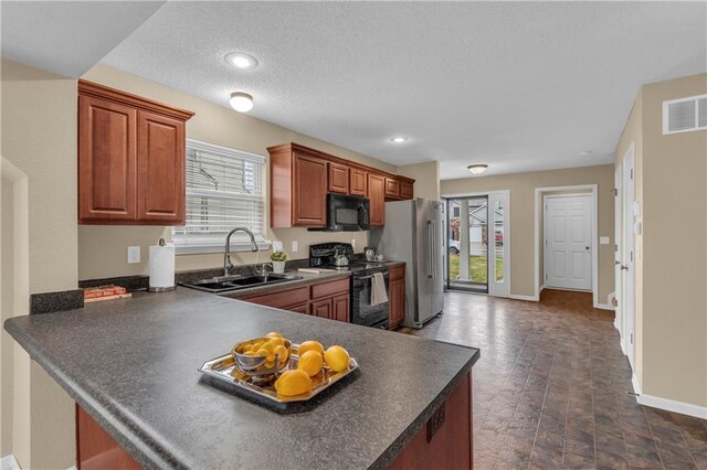 kitchen featuring dark countertops, visible vents, black appliances, and a sink