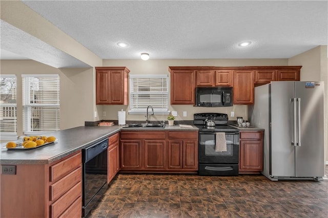 kitchen with black appliances, a sink, dark countertops, a peninsula, and brown cabinetry