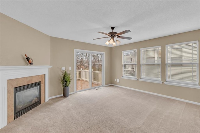 unfurnished living room with a textured ceiling, a fireplace, carpet flooring, baseboards, and ceiling fan