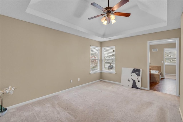 unfurnished bedroom featuring carpet flooring, baseboards, a raised ceiling, and visible vents
