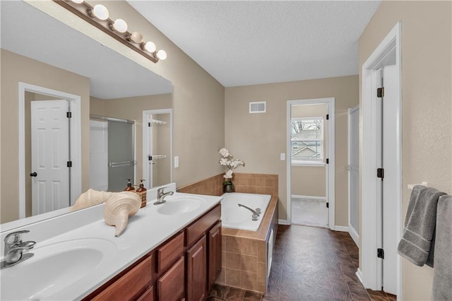 full bathroom featuring a textured ceiling, a stall shower, visible vents, and a sink