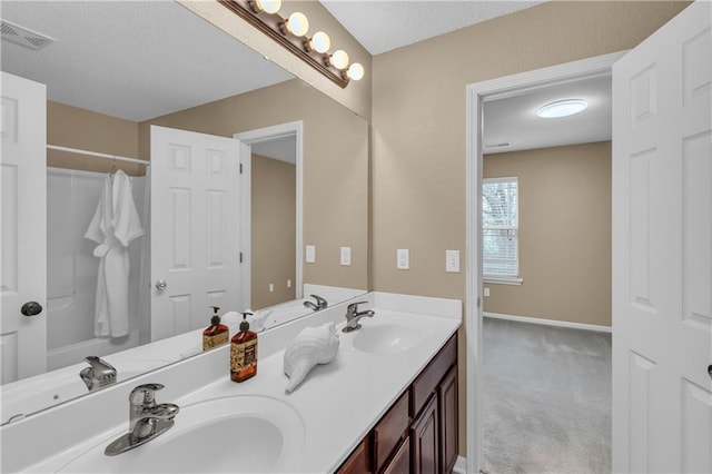 bathroom with a textured ceiling, double vanity, visible vents, and a sink