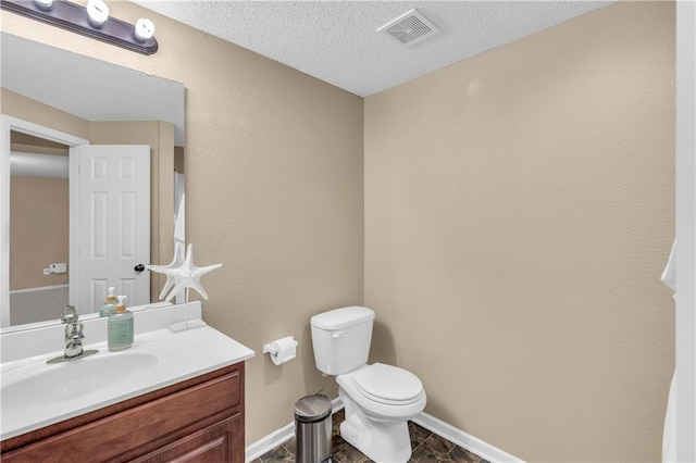 half bath featuring visible vents, toilet, a textured ceiling, baseboards, and vanity