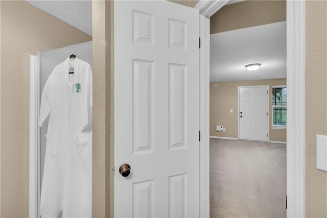 interior space with a textured ceiling, carpet, and baseboards