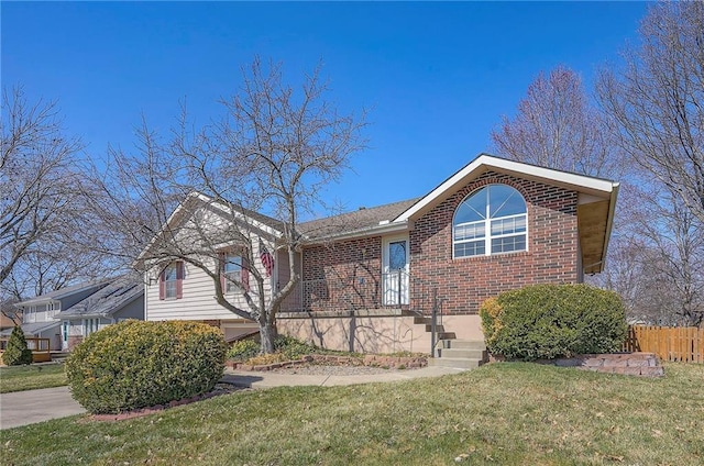 view of front facade featuring brick siding, a front yard, and fence