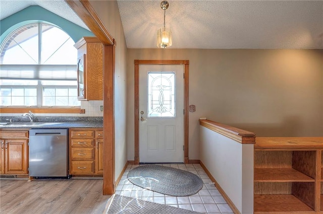 kitchen featuring a sink, plenty of natural light, dishwasher, and brown cabinetry