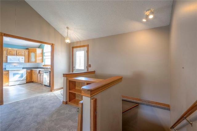 kitchen featuring white appliances, lofted ceiling, hanging light fixtures, a textured ceiling, and light colored carpet