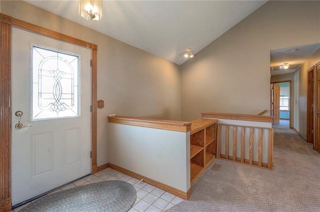 foyer entrance featuring light tile patterned floors, baseboards, lofted ceiling, a textured ceiling, and light colored carpet