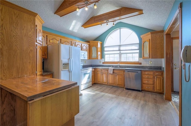 kitchen featuring white appliances, brown cabinetry, light wood-style floors, and lofted ceiling