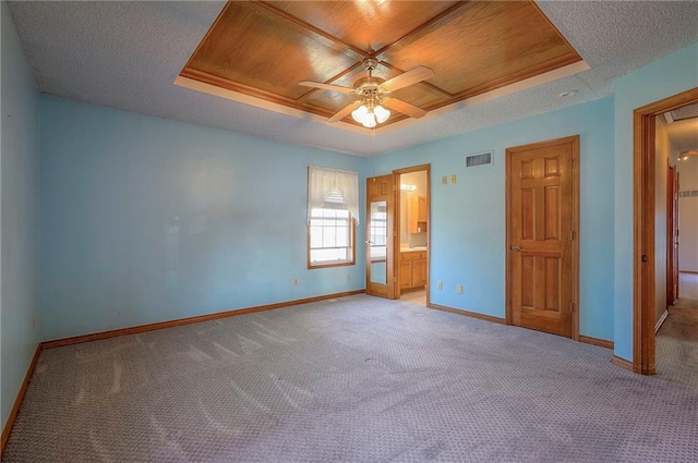 unfurnished bedroom with baseboards, carpet floors, wooden ceiling, a textured ceiling, and a raised ceiling