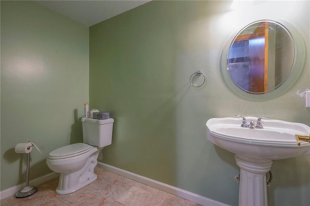 half bathroom with baseboards, toilet, and tile patterned flooring