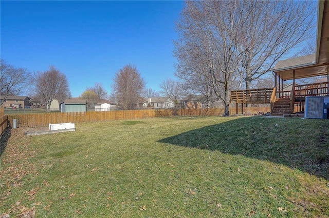 view of yard featuring a deck, a fenced backyard, and stairs