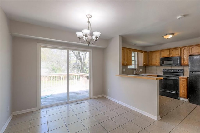 kitchen featuring black appliances, a chandelier, light tile patterned floors, and light countertops