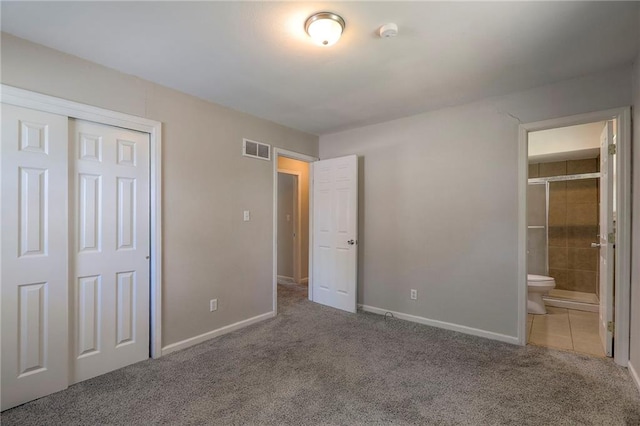 unfurnished bedroom featuring carpet, baseboards, a closet, and ensuite bathroom