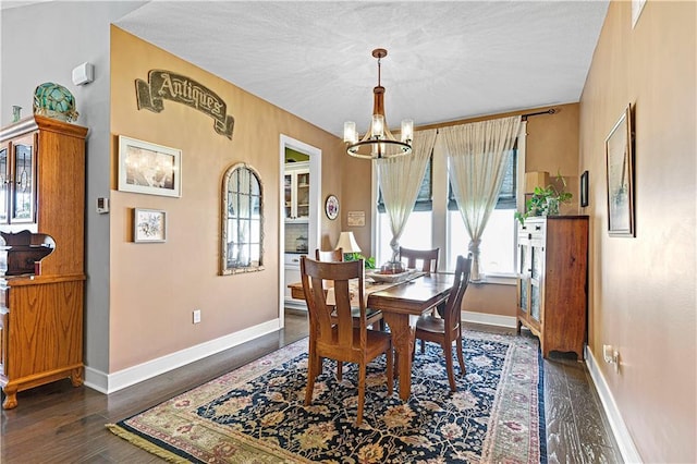 dining room featuring a textured ceiling, wood finished floors, baseboards, and a chandelier