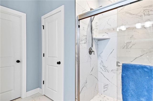 full bath featuring marble finish floor, a stall shower, and baseboards