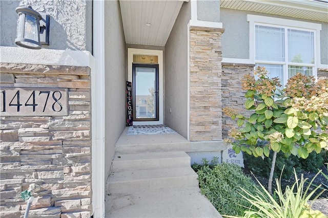 property entrance featuring stone siding and stucco siding