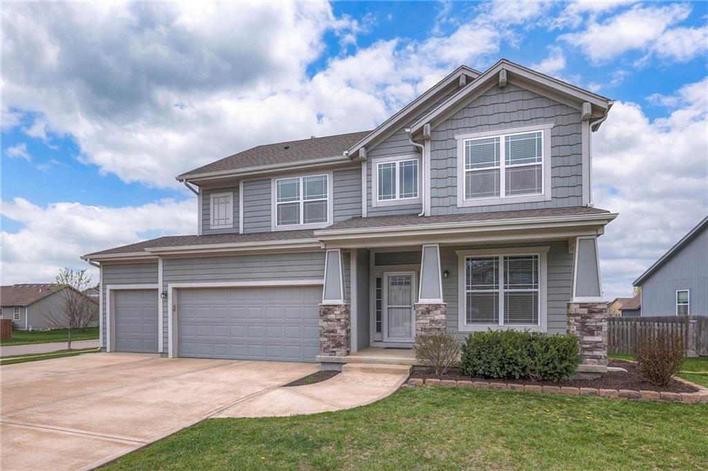 710 N Laurel St, Gardner, KS 66030 - craftsman house with an attached garage, stone siding, driveway, a front yard, and a porch